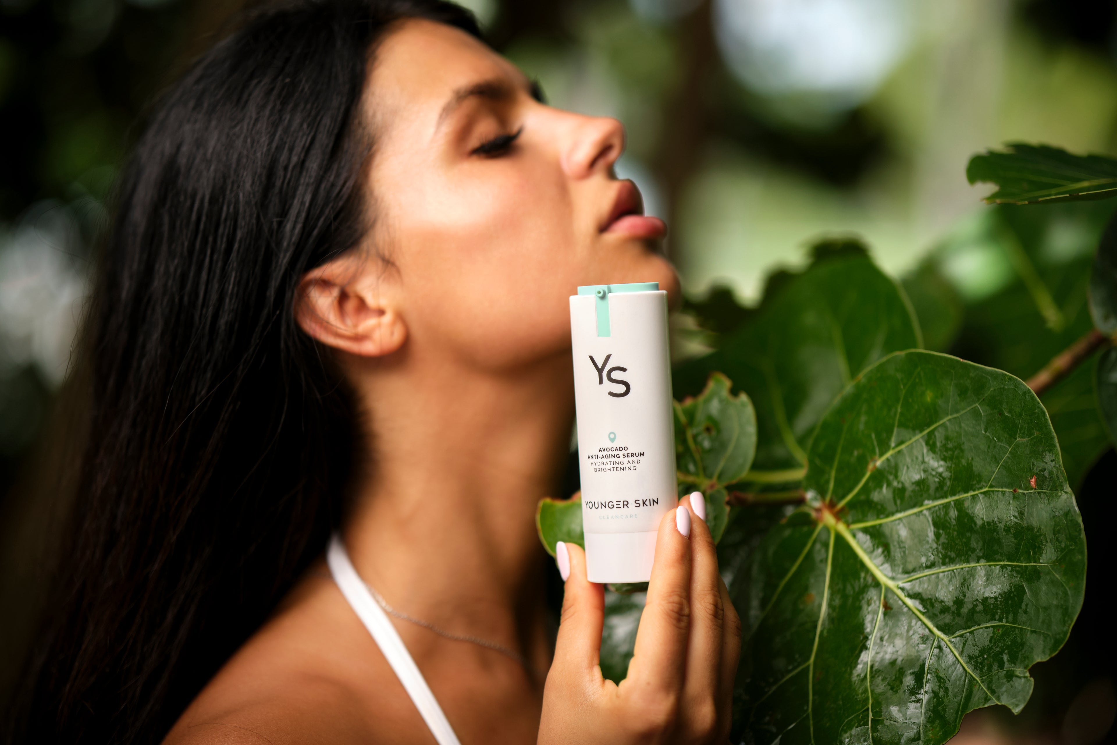 SkinCare Model in tropical environment presenting YoungerSkin Product Bottle with Anti-Aging Serum